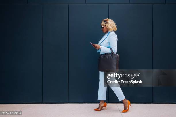 professional woman walking outdoors using smartphone - sapato cinzento imagens e fotografias de stock