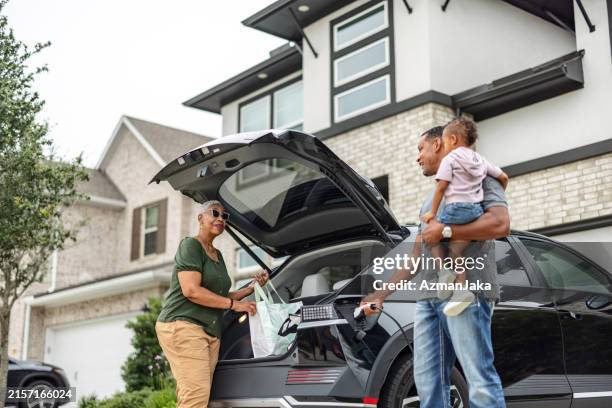 grandmother and grandfather unloading electric vehicle - auto interieur stockfoto's en -beelden