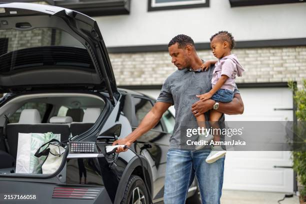 father and son charging electric car at home - electric vehicle charging station stock pictures, royalty-free photos & images