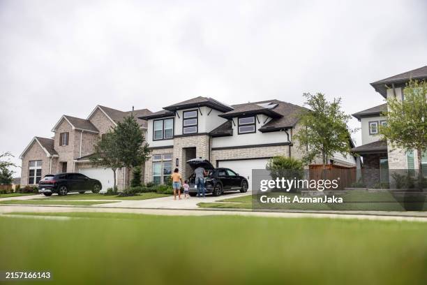 multiethnic family with ev and solar panels on rooftop - auto interieur stockfoto's en -beelden