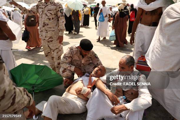 Man effected by the scorching heat is helped by a member of the Saudi security forces as Muslim pilgrims arrive to perform the symbolic 'stoning of...