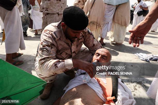 Man effected by the scorching heat is helped by a member of the Saudi security forces as Muslim pilgrims arrive to perform the symbolic 'stoning of...