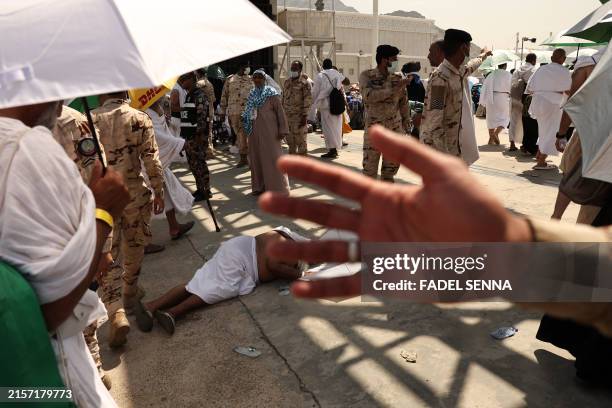 Member of the Saudi security forces prevents people from approaching as a man effected by the scorching heat lies on the ground during the arrival of...