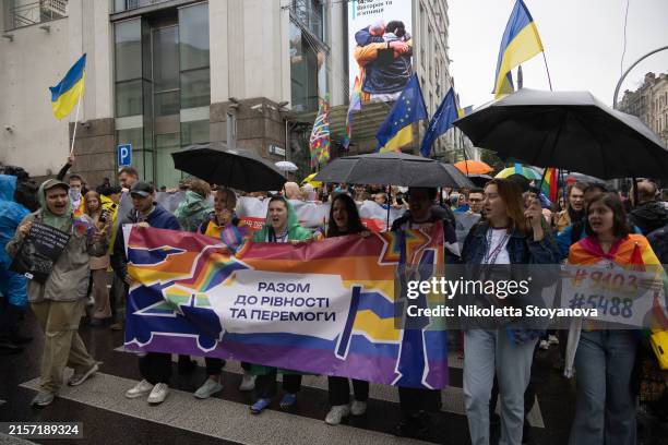 Activists walk with a banner in the Kyiv Pride parade on June 16, 2024 in Kyiv, Ukraine. This year marked the first pride event since Russia's...