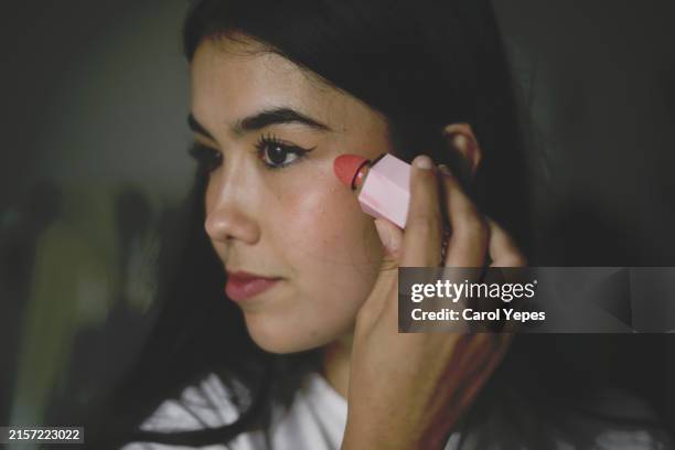 closeup young latina woman applying some blush on cheeks - colorete fotografías e imágenes de stock