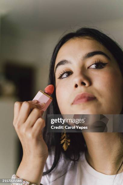 closeup young latina woman applying some blush on cheeks - latina makeup fotografías e imágenes de stock