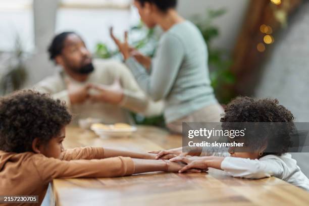 displeased black kids holding hands while their parents are arguing. - echtscheiding stockfoto's en -beelden