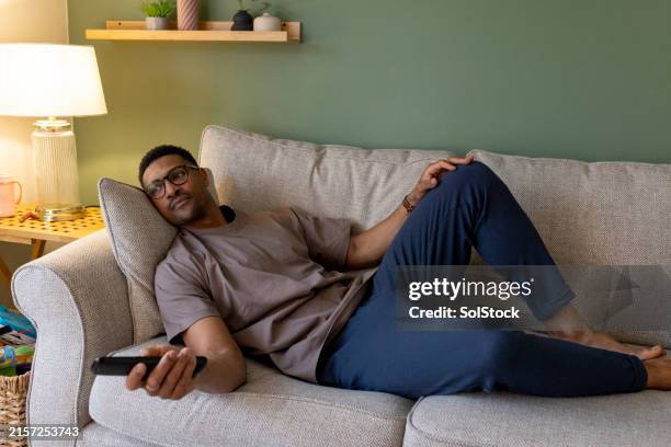 hombre relajándose viendo la televisión - couch potato refrán en inglés fotografías e imágenes de stock
