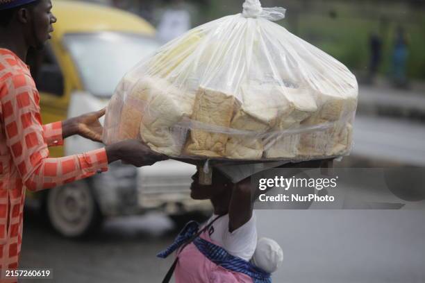 Man who is wanting to buy bread is helping a vendor drop a load of loaves off her head as Muslim faithful are praying to mark the Eid-El-Kabir...