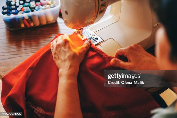 female designer stitching fabric through sewing machine - máquina de costura imagens e fotografias de stock