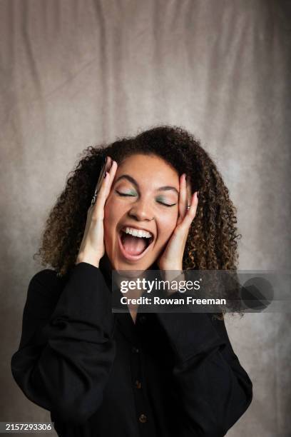 happy woman with eyes closed holding face - bonne nouvelle photos et images de collection