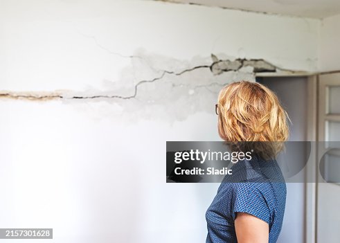 Woman looking at a wall damaged after the earthquake Woman looking at a wall damaged after the earthquake