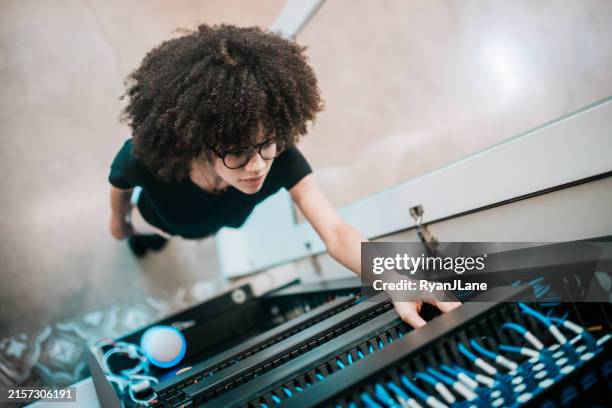 woman adjusting network server panel in modern office setting - cable management stock pictures, royalty-free photos & images
