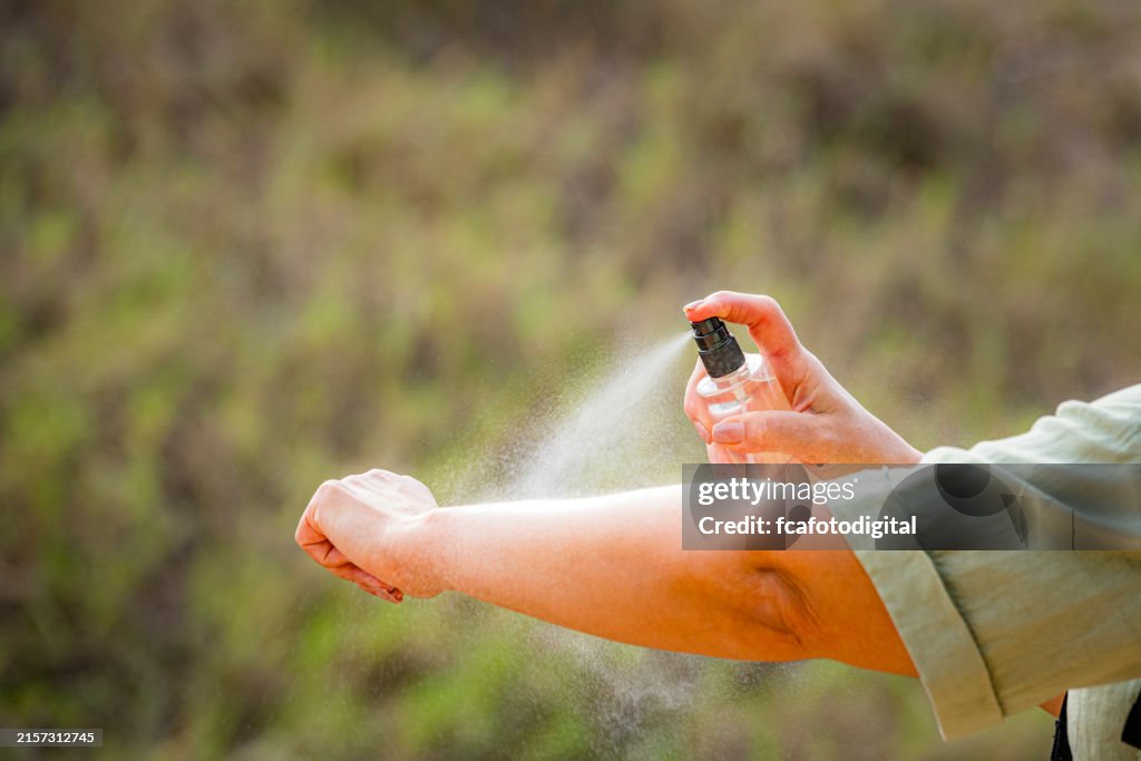 Woman spraying mosquito insect repellent on her arm. Protection against insects bites
