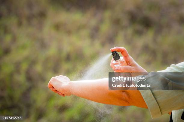 woman spraying mosquito insect repellent on her arm. protection against insects bites - mosquito bite stock pictures, royalty-free photos & images