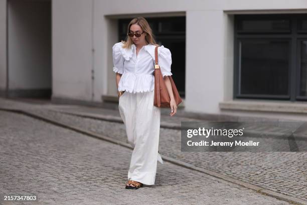 Sonia Lyson is seen wearing sunglasses with havana frame from Givenchy, silver earrings, a golden necklace, a white blouse with puffed sleeves and...
