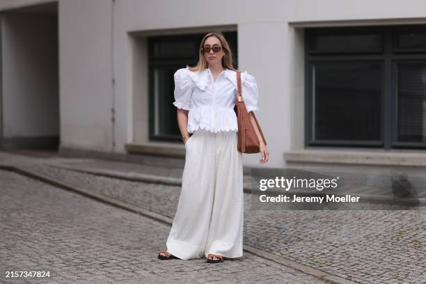Sonia Lyson is seen wearing sunglasses with havana frame from Givenchy, silver earrings, a golden necklace, a white blouse with puffed sleeves and...