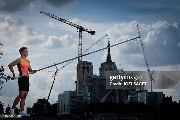 France's pole vaulter Thibaut Collet poses with Notre-Dame de Paris Cathedral in the background undergoing reconstruction work following a massive...