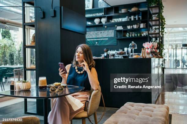 businesswoman using cell phone in hotel cafe - hotel de lujo fotografías e imágenes de stock