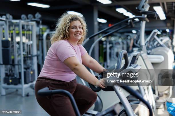 woman smiling on exercise bike - fat bodybuilder stock pictures, royalty-free photos & images