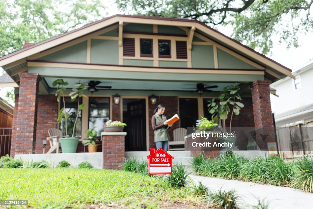 Real estate agent standing in front of the house for sale