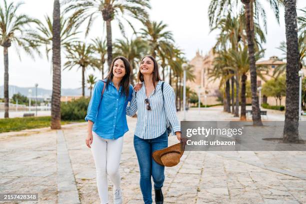 zwei freundinnen, die im park in palma de mallorca in spanien spazieren gehen - palma mallorca stock-fotos und bilder