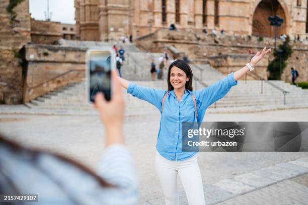 mujer joven tomando fotos de su amiga frente a la catedral de santa maría de palma en palma de mallorca en españa - barroco fotografías e imágenes de stock