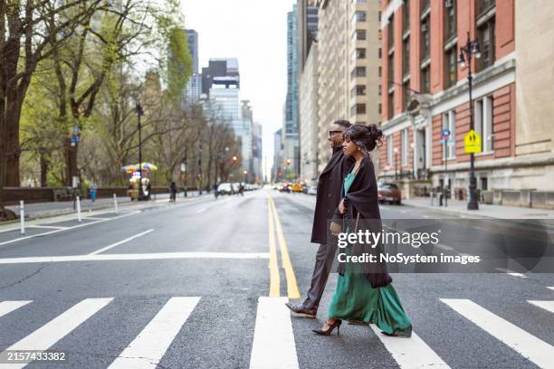 elegantly dressed couple on avenue in manhattan at dusk - couple crossing street stock pictures, royalty-free photos & images