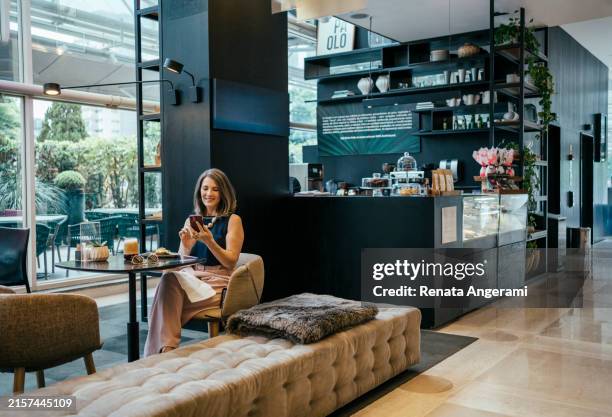 businesswoman using cell phone in hotel cafe - endast en medelålders kvinna bildbanksfoton och bilder
