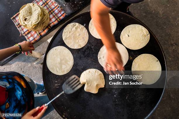 Mexican women cook tortillas on the comal in a tortillería on November 5, 2022 in Morelia, Mexico. Tortillas are an essential element in the Mexican...