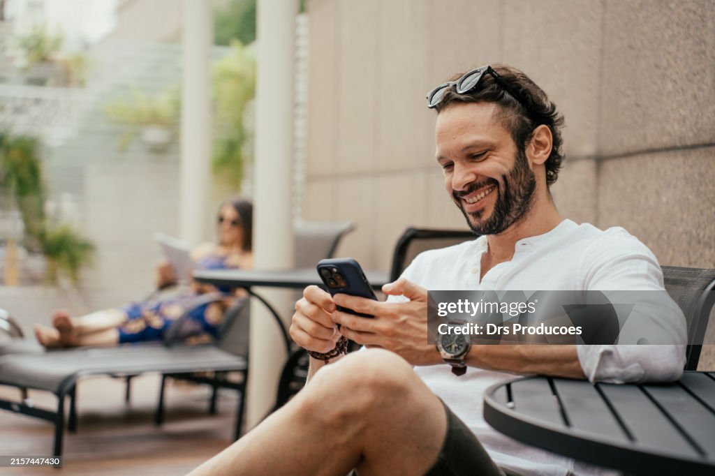 Homme se relaxant au bord de la piscine à l’aide d’un smartphone
