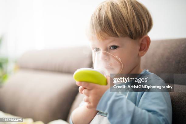a little ill boy using inhaler. - respiratory infection stock pictures, royalty-free photos & images
