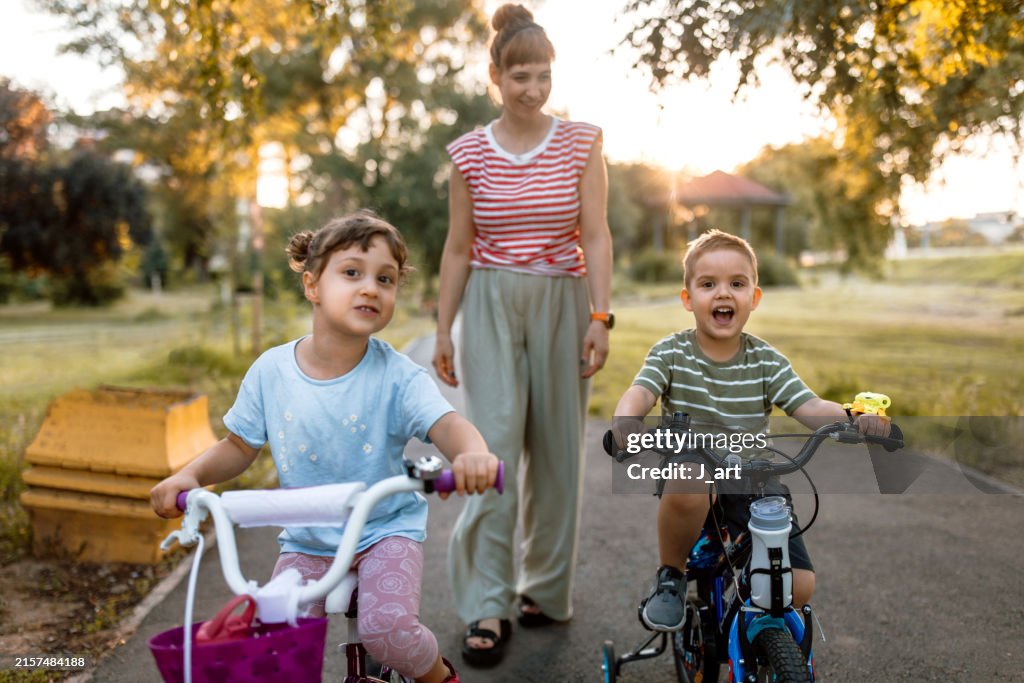 Brother and sister learn to ride a bike in the park.