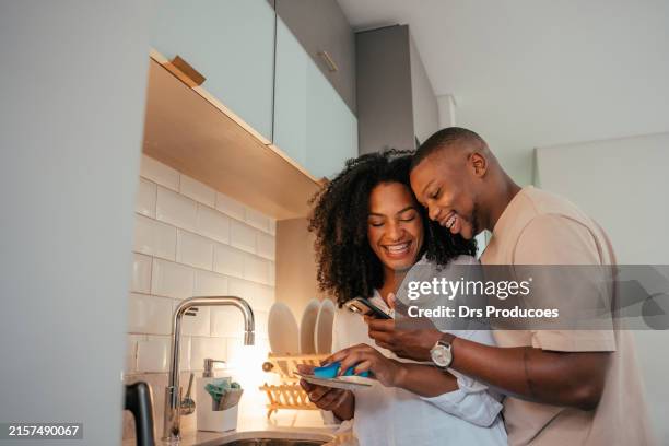 young couple looking at smartphone at home - casal - fotografias e filmes do acervo