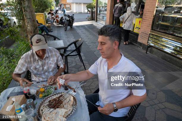 Two Iranian men are eating kebab while sitting at an outdoor restaurant, amidst the early presidential election campaigns, in downtown Tehran, Iran,...