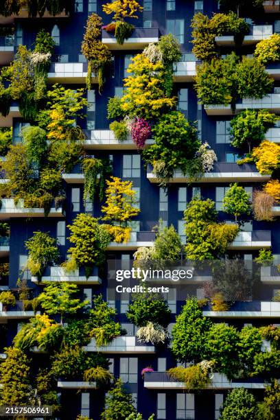 nahaufnahme eines modernen wolkenkratzers mit grünen bäumen und bunten pflanzen auf balkonen wie ein vertikaler wald in mailand, italien - vertikal stock-fotos und bilder