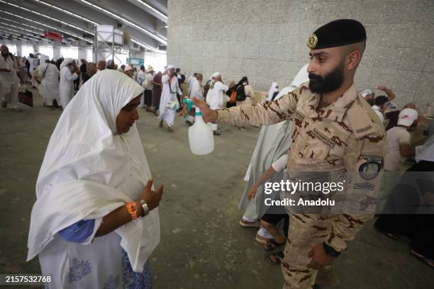 An officer spray water to a woman during a hot day as Muslim pilgrims, coming from all over the world, continue their worship to fulfil the Hajj...