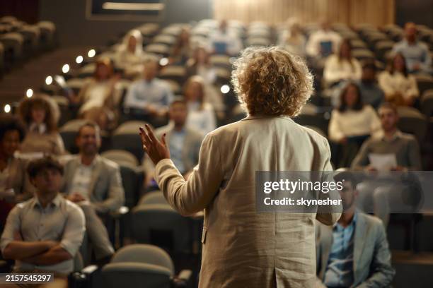 back view of a businesswoman leading a seminar in board room. - luidspreker stockfoto's en -beelden