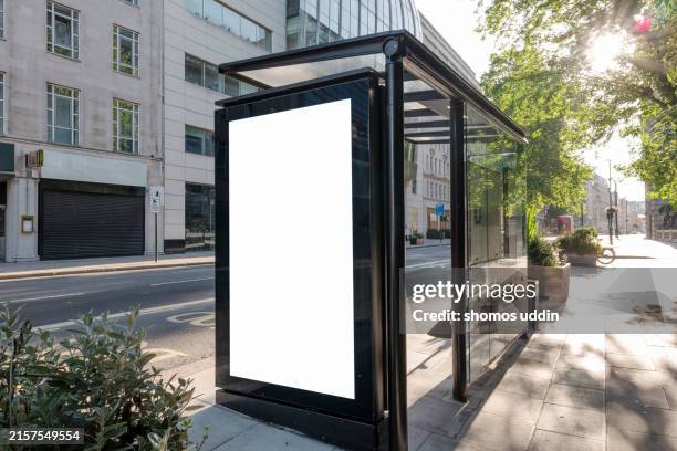 bus stop advertising at a street in london - parada de autobús fotografías e imágenes de stock