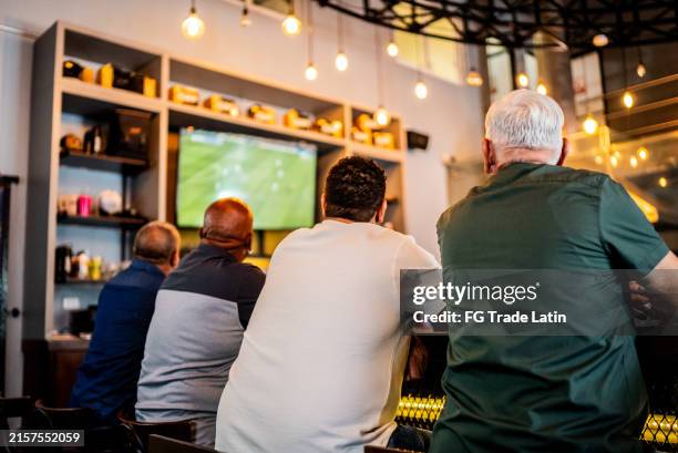ältere männer schauen sich ein fußballspiel an der bar an - kneipe stock-fotos und bilder