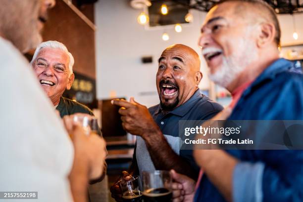 amici anziani che parlano e bevono birra al bar - happy hour foto e immagini stock