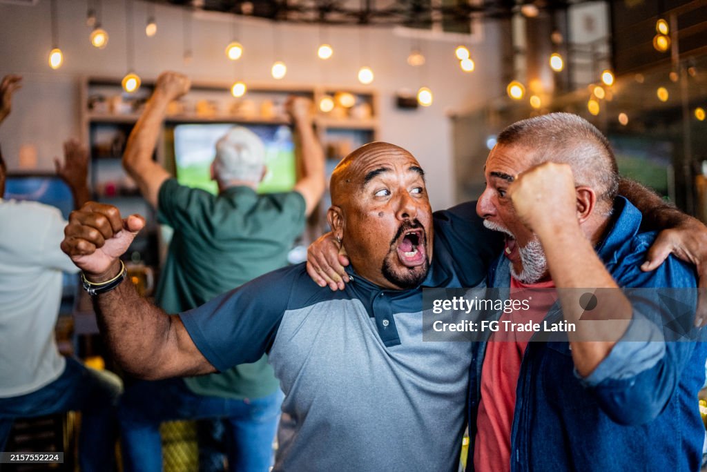 Ältere Fans feiern ein Tor bei einem Sportspiel an der Bar