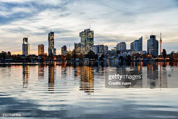 night skyline of donau city (donaustadt), vienna business district. reflection in calm lake. - wien skyline stock-fotos und bilder