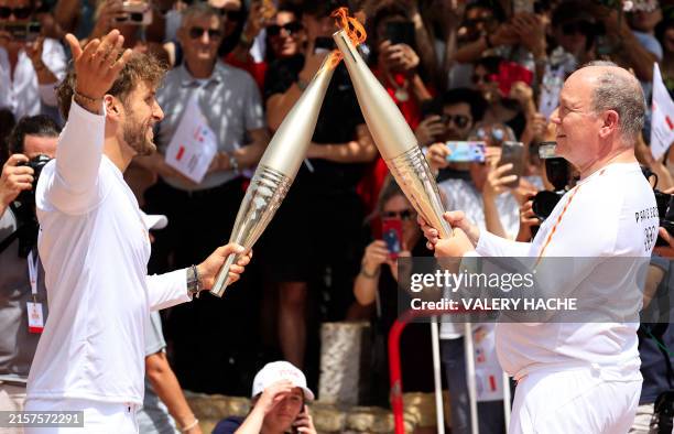 Monegasque bobsledder Rudy Rinaldi and Monaco's Prince Albert II perform the Olympic Flame transfer through a torch kiss with Olympic Flame torches...