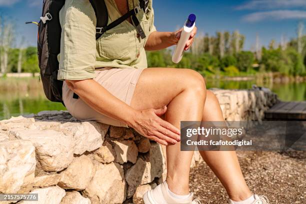 woman explorer applying sunscreen lotion in her leg - zonnebrand stockfoto's en -beelden