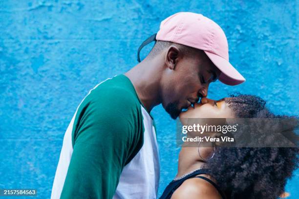 portrait of young african couple kissing isolated on blue background - besar fotografías e imágenes de stock