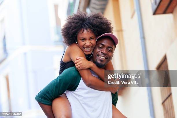 portrait of african american couple having fun dancing outdoors in european city. - carrying a person on shoulders stock pictures, royalty-free photos & images