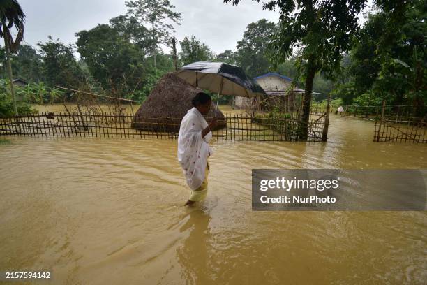 Woman is walking through a flooded road following rains in Changchaki village in Nagaon District of Assam, India, on June 18, 2024.