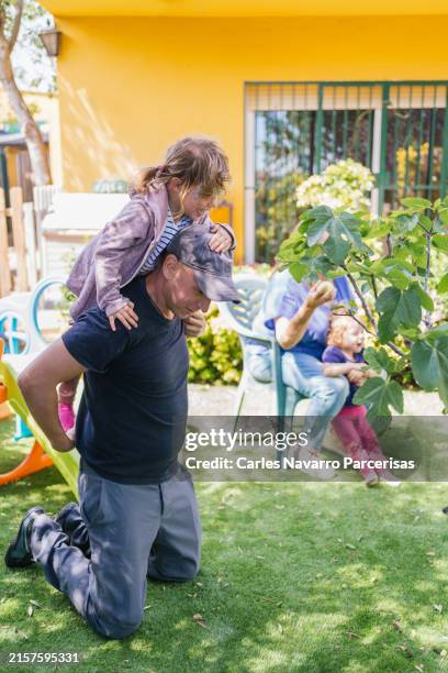 girl with painted face rides on her uncle's shoulders in a playful outdoor setting. - uncle stock pictures, royalty-free photos & images