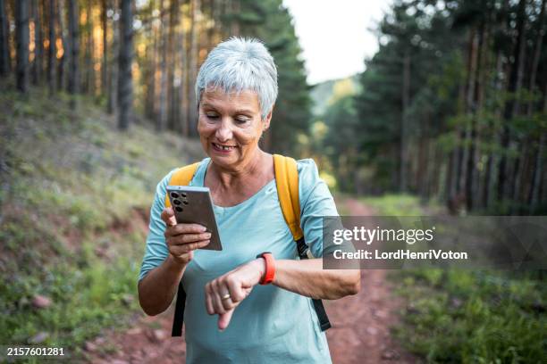 senior hiker woman using a smartphone in the forest - location tracking stock pictures, royalty-free photos & images